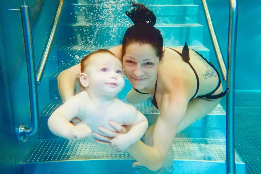 Mama taucht mit Baby im Wasser