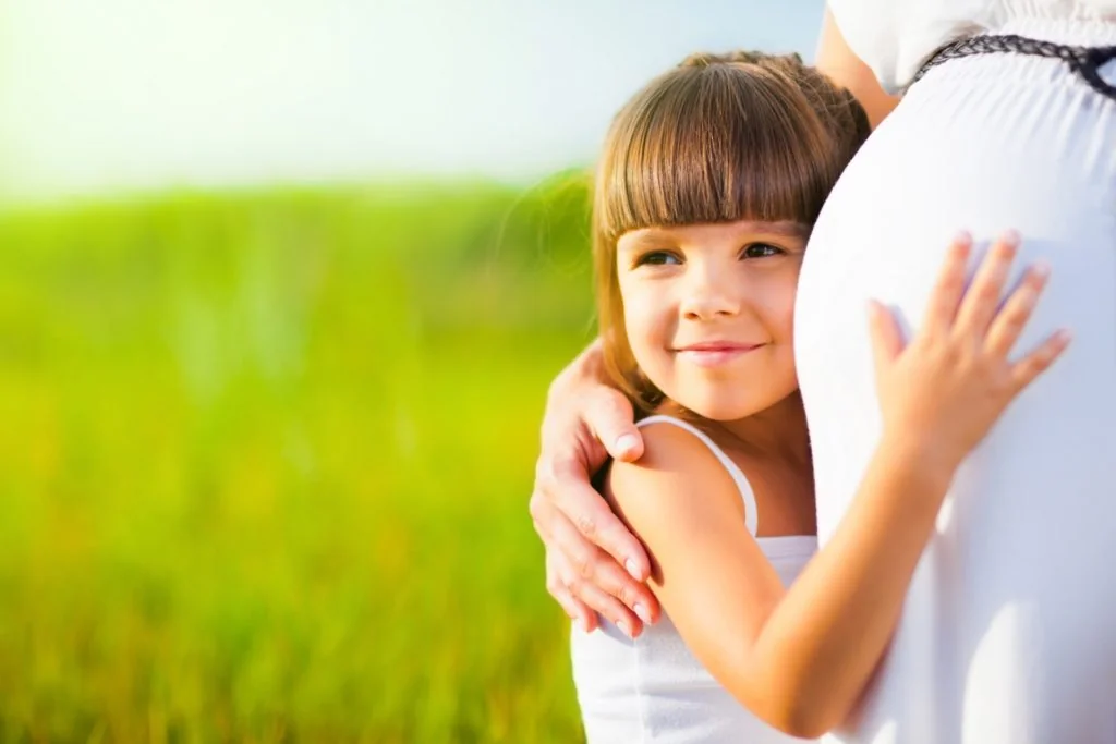 Tochter umarmt Babybauch von Mama
