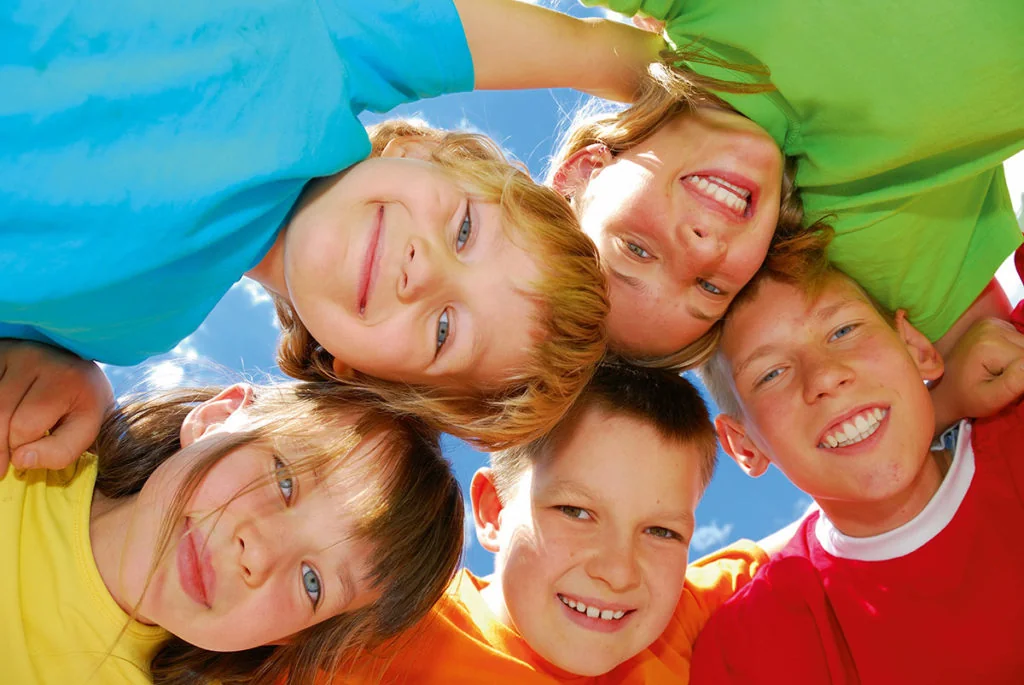 fünf lächelnde Kinder umarmen sich